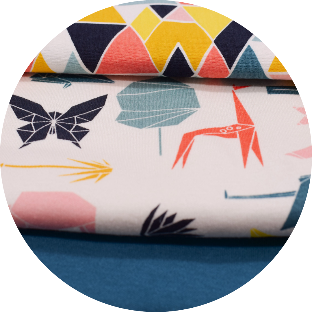 geometric multi colored printed fabrics stacked on top of solid teal fabric