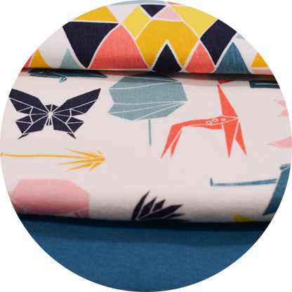 geometric multi colored printed fabrics stacked on top of solid teal fabric 