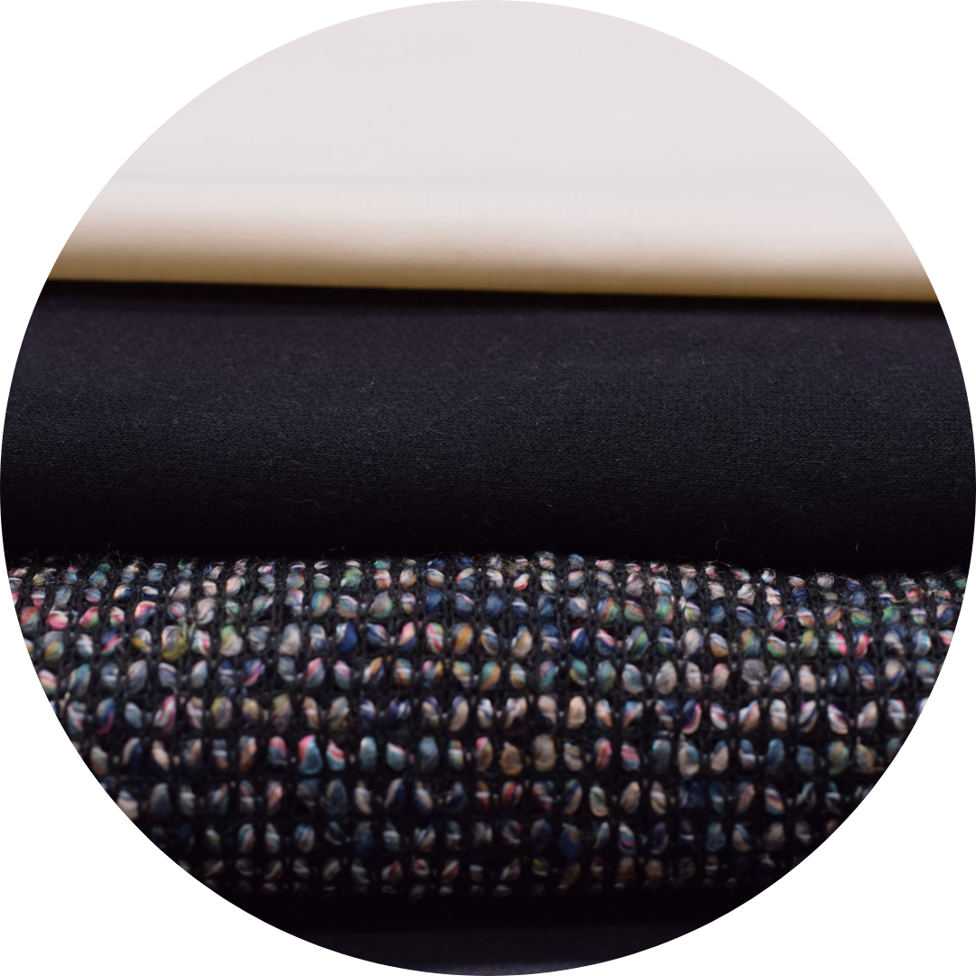 cream poplin, black terry, and multicolor loose weave fabrics stack on one another